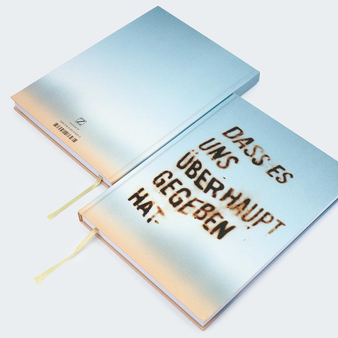 Auf dem Foto sind die Vorder- und Rückseite des Notizbuches nebeneinander auf einer hellgrauen Oberfläche abgebildet. Die Bücher haben ein weiches Farbverlauf-Cover, das von einem warmen Beige am unteren Rand in ein kühles Hellblau am oberen Rand übergeht. Auf der Vorderseite des Notizbuches ist ein unscharfer Schriftzug in zu sehen: „Dass es uns überhaupt gegeben hat.“