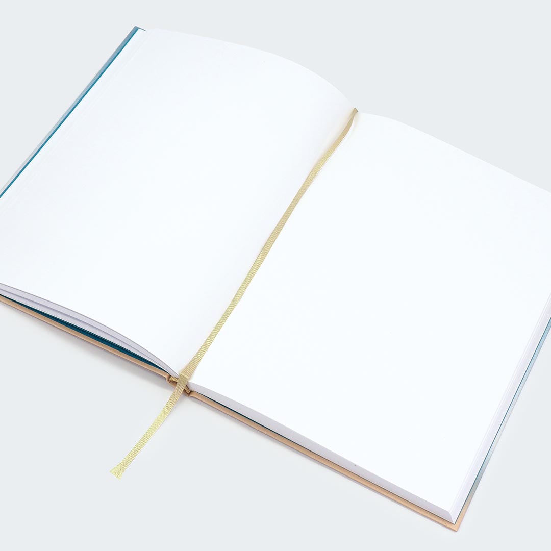 Das Bild zeigt ein aufgeschlagenes Notizbuch mit reinweißen Seiten, ohne Linien oder Karos. In der Mitte ist ein hellgelbes Stoffbändchen als Lesezeichen.