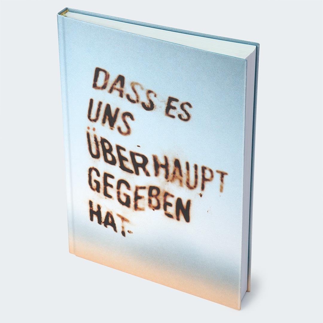 Auf dem Foto ist die Vorderseite des Notizbuches auf einer hellgrauen Oberfläche abgebildet. Das Buch hat ein weiches Farbverlauf-Cover, das von einem warmen Beige am unteren Rand in ein kühles Hellblau am oberen Rand übergeht. Auf der Vorderseite des Notizbuches ist ein unscharfer Schriftzug in zu sehen: „Dass es uns überhaupt gegeben hat.“
