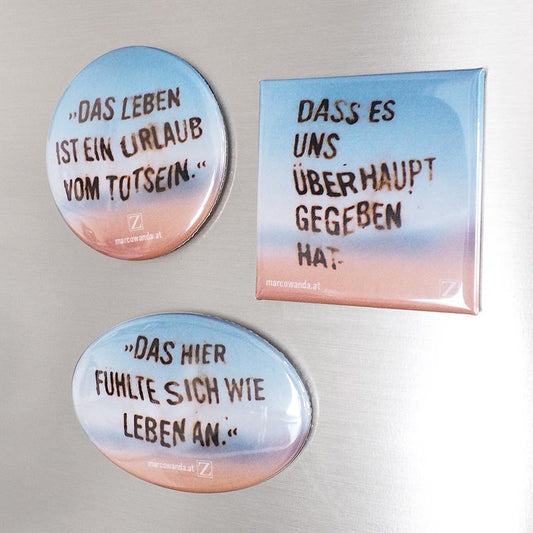Abgebildet sind drei Kühlschrankmagnete in unterschiedlichen Formen mit Zitaten auf einem sanften Farbverlauf im Sonnenuntergangsdesign.
Runder Magnet: „Das Leben ist ein Urlaub vom Totsein.“
Eckiger Magnet: „Dass es uns überhaupt gegeben hat.“
Ovaler Magnet: „Das hier fühlte sich wie Leben an.“