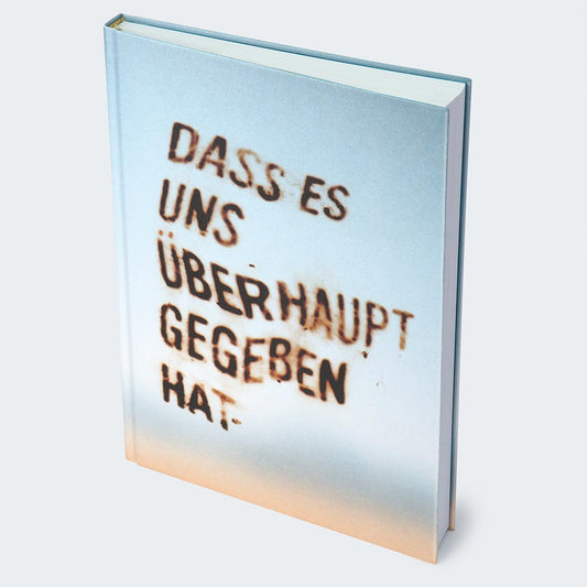 Auf dem Foto ist die Vorderseite des Notizbuches auf einer hellgrauen Oberfläche abgebildet. Das Buch hat ein weiches Farbverlauf-Cover, das von einem warmen Beige am unteren Rand in ein kühles Hellblau am oberen Rand übergeht. Auf der Vorderseite des Notizbuches ist ein unscharfer Schriftzug in zu sehen: „Dass es uns überhaupt gegeben hat.“